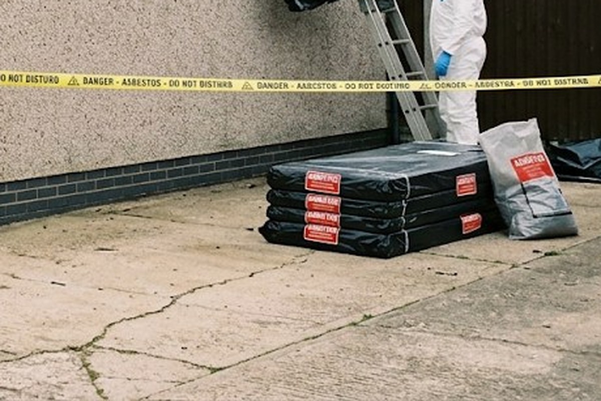 Wrapped asbestos sheets with warning labels stacked on a drive